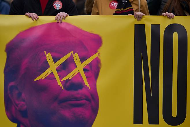 지난 21일(현지시간) 스페인 마드리드에서 시민들이 이란과의 전쟁 종식을 촉구하는 시위를 벌이며 도널드 트럼프 미국 대통령의 모습이 그려진 현수막을 들고 있다. AP연합뉴스