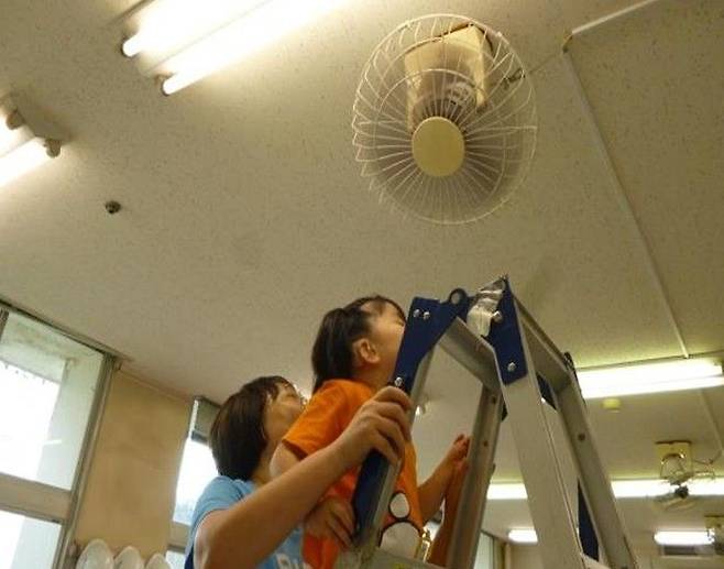 시각과 청각 장애를 중복으로 가진 전맹 유아가 교사의 도움을 받아 사다리에 올라가 천장에 매달린 선풍기를 직접 만져보고 있다. 바람이 어디서 불어오는지 '경험'을 통해 세상을 인지하게 하는 교육의 한 장면이다. 밀알복지재단 제공