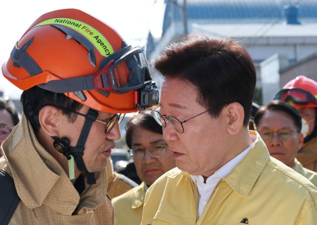 ▲이재명 대통령이 21일 대전 대덕구 안전공업 건물의 대형 화재 현장을 찾아 상황보고를 받고 있다. ⓒ연합뉴스