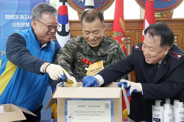 24일 경기도 김포시 소재 해병대 제2사단에서 진행한 '저소득 참전용사 및 국가유공자 지원 봉사활동'에서 정상혁 신한은행장(왼쪽), 최영길 해병대 제2사단장(가운데), 홍봉식 구세군 커뮤니케이션스국장이 생필품 키트 제작 봉사활동을 하고 있다. /신한은행
