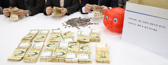 지난해 12월 30일 노송동 주민센터에서 직원들이 '얼굴 없는 천사'가 두고 간 성금을 확인하고 있다. 액수를 세어 보니 9004만6000원이었다. 지난해까지 26년간 ‘얼굴 없는 천사’의 총 기부액은 11억3488만2520원에 달한다. [뉴스1]