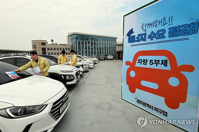 공공부문 승용차 5부제 의무 강화 (광주=연합뉴스) 조남수 기자 = 24일 오후 광주 북구 효죽2주차장 4층에서 구청 에너지정책팀 직원들이 차량 유리창에 승용차 요일제 안내문을 부착하고 있다. 2026.3.24 iso64@yna.co.kr