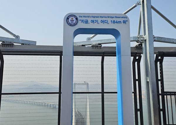 '더 스카이 184' 상층부에 위치한 세계 최고 높이 해상 교량 전망대를 안내하는 기네스 북 조형물 뒤로 청라하늘대교가 보이고 있다. 2026.03.25. [사진 = 김예빈 기자]