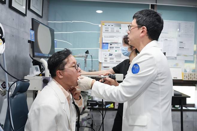 16일 서울 중구 보아스이비인후과에서 오재국 대한이비인후과의사회 서울지회장(오른쪽)이 본보 기자의 혀를 잡고 후두 내시경을 통해 상태를 확인하고 있다. 보아스이비인후과 제공