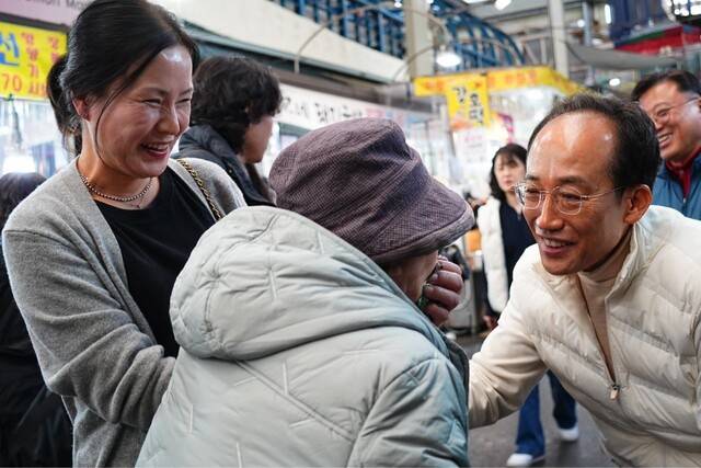 국민의힘 대구시장 예비후보인 추경호 국민의힘 의원이 지난 21일 대구 서문시장에서 흰색 점퍼를 입고 유권자들과 인사를 나누고 있다. 추경호 의원 페이스북 갈무리