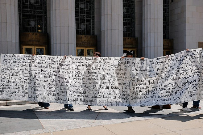 25일(현지시간) 미국 로스앤젤레스에 있는 캘리포니아주 1심 법원 앞에서 부모들이 자녀의 이름이 적힌 현수막을 들고 있다. 이들 부모는 메타의 SNS와 구글의 유튜브가 자녀의 정신건강을 해쳤다고 항의했다. 로이터연합뉴스