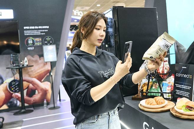 김효정 선수가 커넥트 플러스 존에서 스마트폰을 들고 섭취 영양 정보를 스캔하고 있다. [가민 제공]
