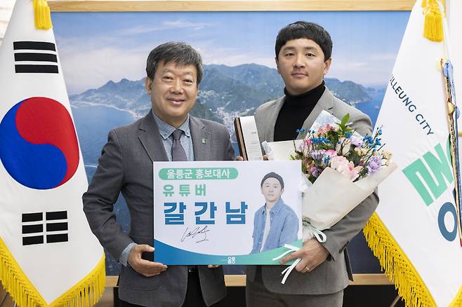 남한권 울릉군수가 유튜버 ‘갈간남’ 엄정운 씨에게 홍보대사 위촉패를 전달한 뒤 기념사진을 찍고 있다. /울릉군 제공