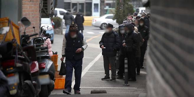 설 명절 연휴를 이틀 앞둔 지난달 19일 서울 종로구 탑골공원에서 노인들이 인근 무료급식소에서 점심 배식을 받기 위해 줄을 서고 있다.뉴시스