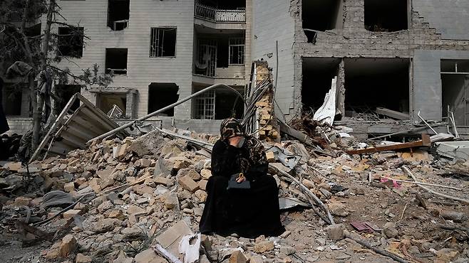 지난 12일, 이란 테헤란에서 한 여성이 지난 미국과 이스라엘의 공습으로 파괴된 건물 앞에서 흐느끼고 있습니다.(AP)