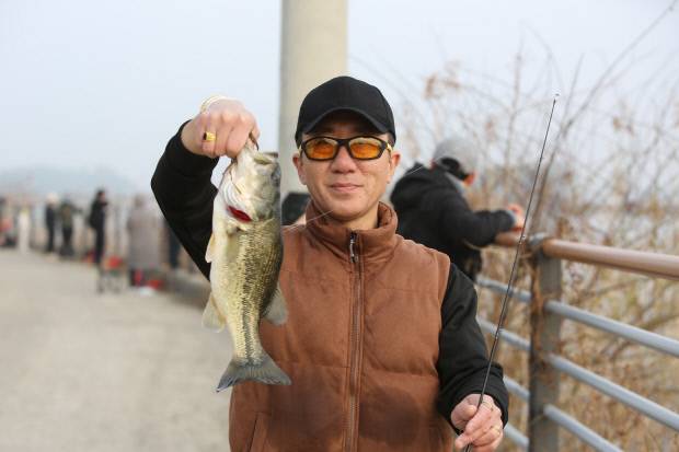 낚은 물고기를 손에 들고 참가자가 행복한 웃음을 짓고 있다.