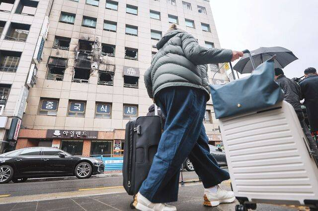한 관광객이 지난 15일 3, 4층이 불에 탄 서울 중구 소공동의 캡슐호텔 앞을 지나가고 있다. 연합뉴스
