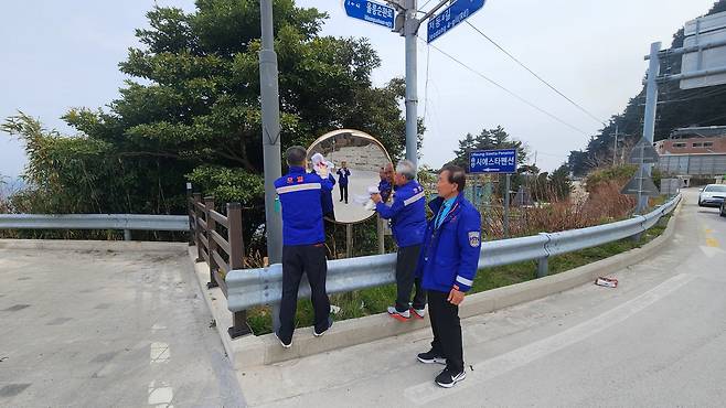 ‘작은 거울 속에 담긴 큰 안전’ 지난 30일 울릉도 해안도로 곳곳에서 모범운전자들이 반사경을 닦고 있다. /모범운전자회 울릉지회 제공