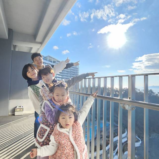 새해를 맞아 지난 1월 경남 거제로 여행을 떠난 권태형·김한나 씨 가족이 숙소 베란다에서 막 떠오른 태양을 손으로 가리키고 있다. 권태형 씨 제공