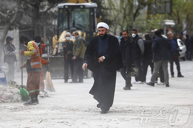 29일(현지시간) 이란 테헤란에서 한 성직자가 공습으로 피해를 입은 카타르 매체 알아라비 TV 건물 근처를 걷고 있다. 2026.03.29. ⓒ 로이터=뉴스1
