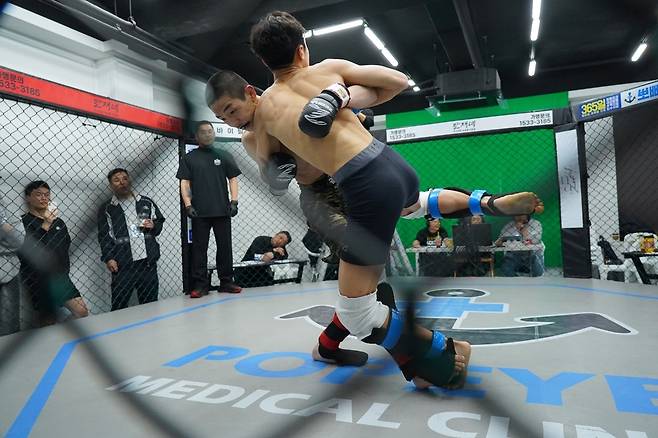 플라이급 챔피언 문순수가 3월 KMMA 타이틀 방어전에서 도전자로 나선 밴텀급 챔피언 변상민의 발목을 걸어 넘어뜨리려 하고 있다. [대회사 제공]