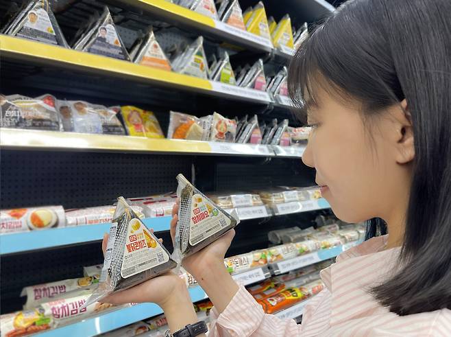 GS25가 역대 최고 스펙으로 삼각김밥 '풀체인지 리뉴얼'을 추진하고 있다. 모델이 GS25가 '풀체인지 리뉴얼'을 완료한 '더큰 삼각김밥' 시리즈를 살펴보고 있다.(사진제공=GS리테일)