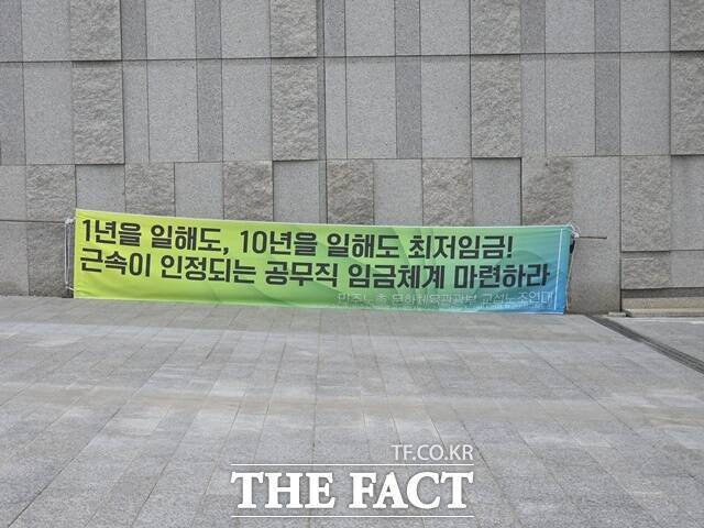 최저임금제도는 지난 1986년 도입돼 1988년부터 시행됐다. 저임금 노동자의 최소한 생계를 보장하기 위한 취지였다. 그러나 지난 38년간 비정규직 등 저임금 노동자에게 최저임금은 '하한선'이 아닌 사실상 '기준임금'으로 작동하고 있다는 지적이 나온다. 사진은 지난해 국립중앙박물관 주변 '1년을 일해도 10년을 일해도 최저임금. 근속이 인정되는 공무직 임금체계 마련하라' 문구가 담긴 현수막이 펄럭이고 있는모습. /온라인 커뮤니티' X(옛 트위터)' 갈무리