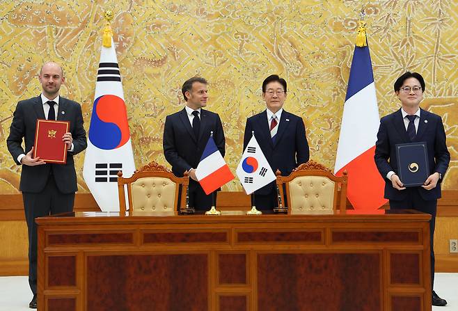 Kim Jung-kwan, minister of trade, industry and energy, and French Foreign Minister Jean-Noel Barrot pose for a commemorative photo after exchanging a letter of intent on cooperation in critical mineral supply chains, in the presence of President Lee Jae Myung and French President Emmanuel Macron at Cheong Wa Dae in Seoul on Friday. (Yonhap)