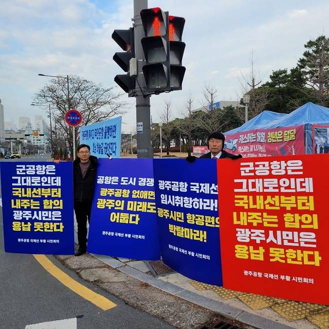 광주시청 앞에서 광주공항 국제선 부활 시민회의가 민간공항 선이전에 반대하는 손팻말을 들고 있다.