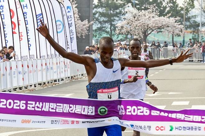 케냐의 아이삭 킵케보이 투가 ‘2026 군산새만금마라톤대회’에서 대회 신기록(2시간7분15초)으로 결승선에 도착하며 두 팔을 뻗고 있다. 군산시 제공