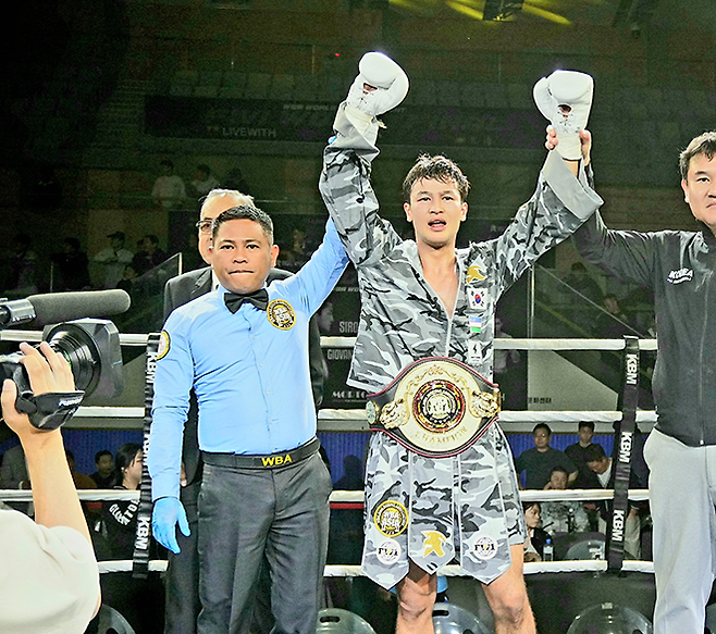 세계복싱협회 라이트급 아시아 챔피언 최시로가 2026년 4월 경기도 남양주체육문화센터 특설 링에서 타이틀 2차 방어 성공 선언을 받고 있다. 오른쪽은 FW1 최완일 대표. 사진=한국복싱커미션 KBM