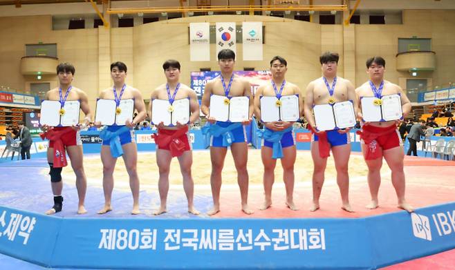 '제80회 전국씨름선수권대회' 대학교부 개인전에서 1위를 차지한 김현우(한림대학교), 이용수(울산대학교), 강준수(경기대학교), 박주환(울산대학교), 김민규(동아대학교), 전민규(영남대학교), 이혁준(인하대학교)가 메달을 메고 상장을 들고 기념사진을 찍고 있다(왼쪽부터). /사진=대한씨름협회 제공