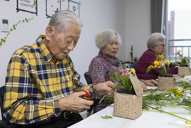 지난해 10월 대전 대덕구의 케어안심주택 ‘늘봄채’에 입주해 부인과 생활하고 있는 장덕기(92세, 사진 맨왼쪽)씨가 꽃꽂이 프로그램에 참여하고 있다.[보건복지부 제공]