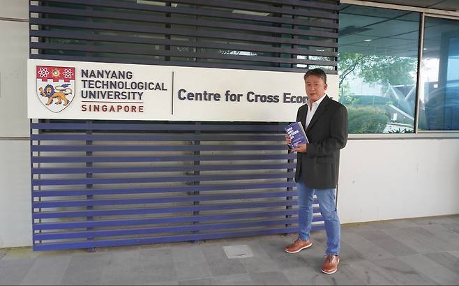 지난 10일 싱가포르 난양공대 변환경제센터 앞에서 조남준 교수가 최근 펴낸 『대학의 미래는 싱가포르에 있다』를 소개하고 있다. 사진 NTU