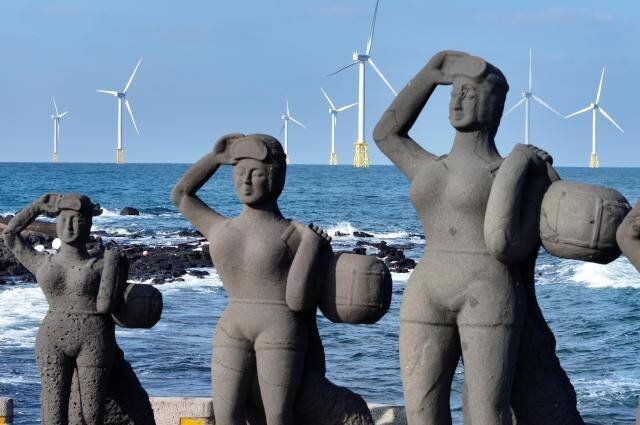 제주도 해녀상 뒤 바다 위에 한림 해상풍력단지 발전기들이 보인다. 연합뉴스