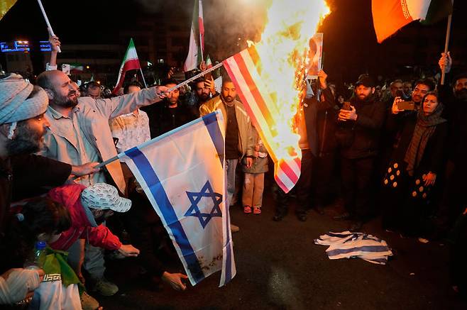 [테헤란=AP/뉴시스] 8일(현지 시간) 미국-이스라엘과 2주간의 휴전이 발표된 이후 이란 테헤란 이슬람혁명광장에 모인 이란 친정부 시위대가 미국과 이스라엘 국기를 불태우고 있다. 2026.04.08.