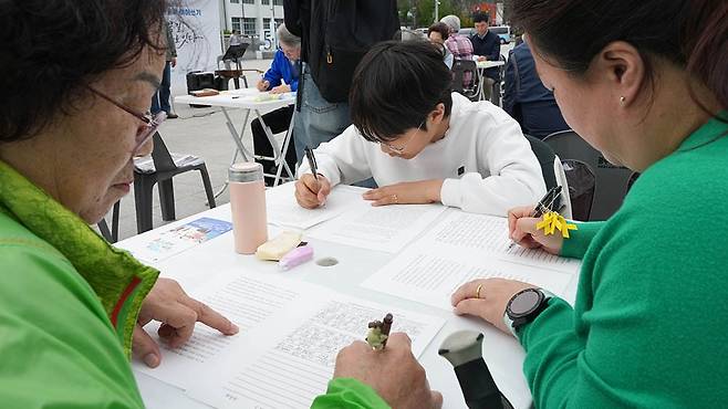 ‘전태일의 꿈, 필사로 잇다’ 행사가 14일 광주 동구 5·18민주광장에서 열려 참가자들이 전태일 평전 손글씨 이어쓰기(필사)를 하고 있다./조영권 기자