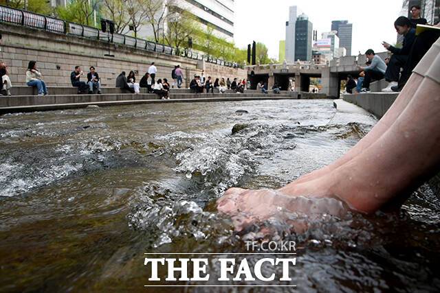 서울 낮 최고 기온이 28도까지 오른 14일 오후 서울 종로구 청계천에서 한 직장인이 청계천에 발을 담그고 있다. /박상민 기자