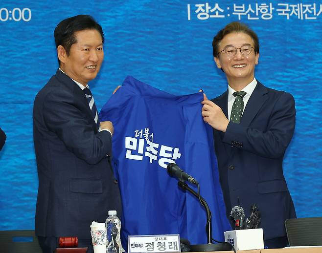 정청래 더불어민주당 대표가 15일 오전 부산 동구 부산항국제전시컨벤션센터에서 열린 부산 현장 최고위원회에서 전재수 부산시장 후보에게 파란 점퍼를 입혀주기 전 들어 보이고 있다. [연합]