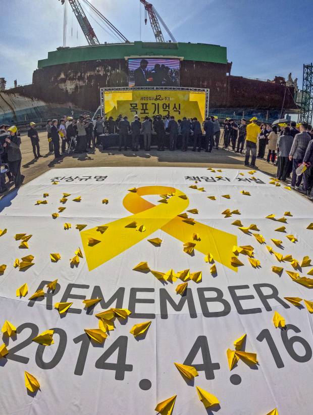 세월호 참사 12주기인 16일 전남 목포신항에서 열린 ‘세월호 목포 기억식’에서 참석자들이 희생자들을 추모하는 대형 현수막 너머로 헌화하고 있다.    /목포=김진수 기자 jeans@kwangju.co.kr