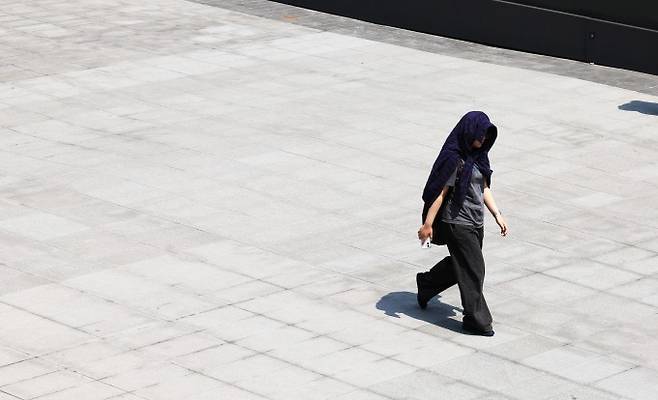 낮 최고기온이 27도까지 오르며 예년 기온을 웃돈 15일 서울 광화문 광장에서 한 시민이 겉옷으로 햇볕을 가리고 걷고 있다. 연합뉴스 제공