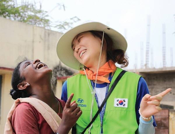 해피무브 봉사단에 참여한 자원봉사자가 현지 여성과 대화를 나누며 환하게 웃고 있다 [사진 제공=현대차그룹]