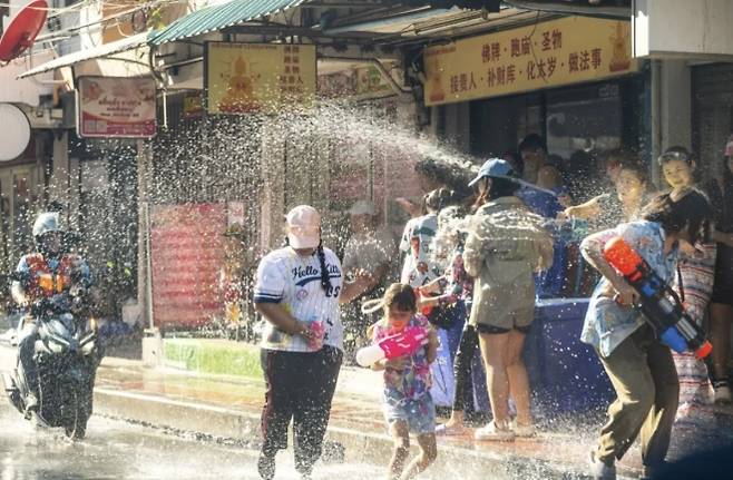 2026년 4월 13일, 태국 방콕에서 송크란 축제 기간 동안 한 여성과 아이가 물보라를 맞으며 걷고 있다. 주마프레스닷컴 제공