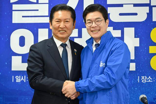 정청래(왼쪽) 더불어민주당 대표가 17일 서울 용산구 강태웅 민주당 용산구청장 후보 선거사무소에서 열린 최고위원회의에서 정원오 민주당 서울시장 후보에게 점퍼를 입혀준 뒤 악수하고 있다. 박시몬 기자