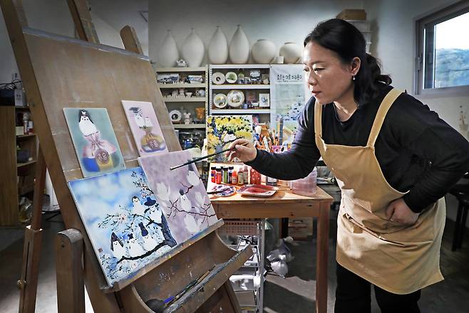 Ceramic painter Kim Eun-kyung paints on a white porcelain slab at her studio in Seorak-myeon, Gapyeong County, Gyeonggi. [PARK SANG-MOON]