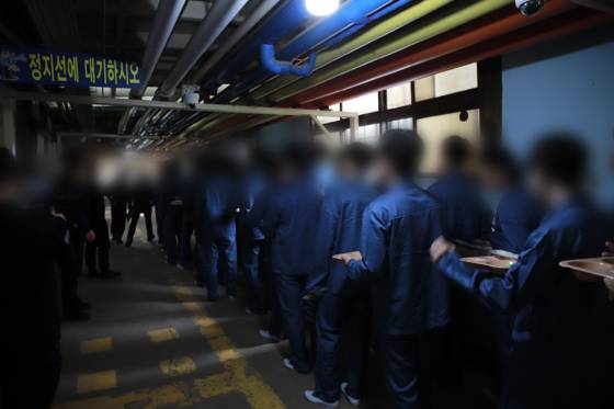 각자 식판과 수저를 받은 뒤 거실로 들어가는 '일일 수용자' 법무부 출입 기자단. 하얀색 고무신을 신었다.〈사진=법무부 제공〉