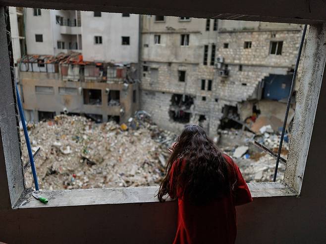 18일(현지시간) 레바논 나바티예에서 이스라엘 공습을 피해 가족과 함께 베이루트로 피신했다가 10일간의 휴전 발효 후 귀가한 한 여성이 파손된 아파트 창문 너머를 바라보고 있다. 로이터=연합뉴스