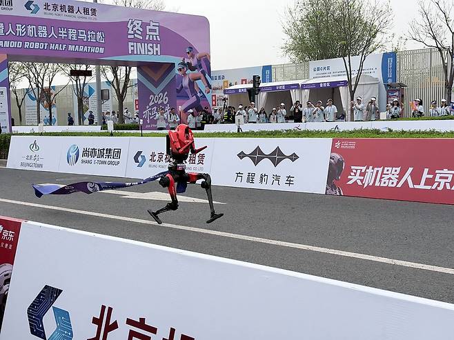 19일 중국 베이징에서 개최된 ‘베이징 이좡 휴머노이드 로봇 하프 마라톤’ 참가 로봇이 결승선 테이프를 매단 채 달리고 있다. 신경진 특파원