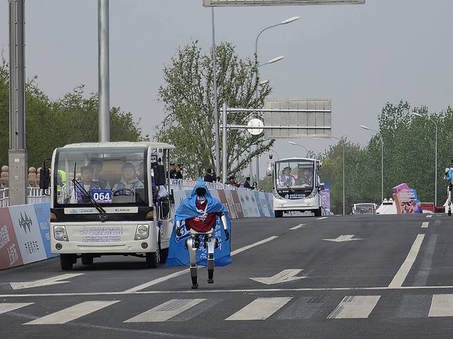 19일 중국 베이징시 이좡에서 개최된 ‘제2회 휴머노이드 로봇 하프마라톤 대회’에 참가한 한 로봇이 망토를 두른 채 달리고 있다. [연합뉴스]