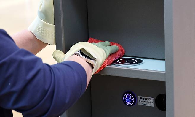 인천국제공항 제2 여객터미널 핸드폰 충전대에서 이용객들이 깨끗하게 사용할 수 있게 인천공항운영서비스 직원이 먼지를 제거하고 있다.