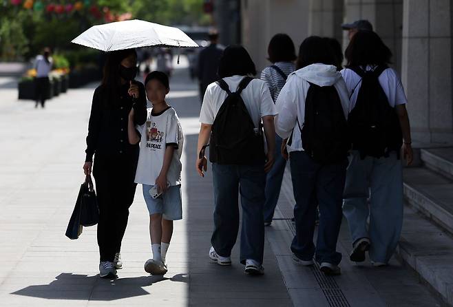 서울 낮 최고기온이 29도를 기록하며 초여름 날씨를 보인 19일 서울 종로구 광화문광장에서 시민들이 양산과 그늘로 햇볕을 피하고 있다. 뉴시스