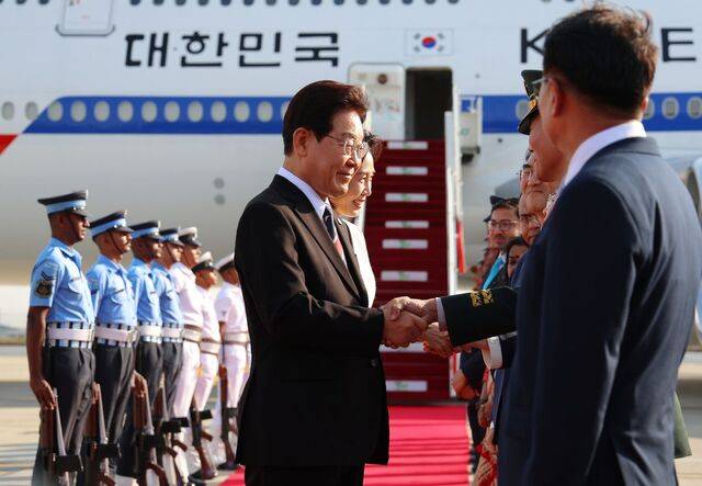 이재명 대통령과 김혜경 여사가 19일(현지시간) 인도 뉴델리 팔람 공군기지에 도착해 영접 인사들과 악수를 하며 웃고 있다. 연합뉴스