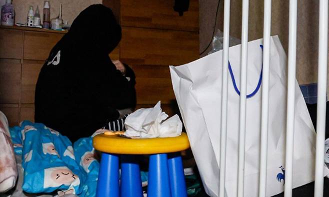 청소년 시기 방임 피해를 겪은 수빈(가명·20)이 후드티를 덮어쓴 채 자신의 방 한가운데에 앉아 있는 모습.&nbsp;유희태 기자.