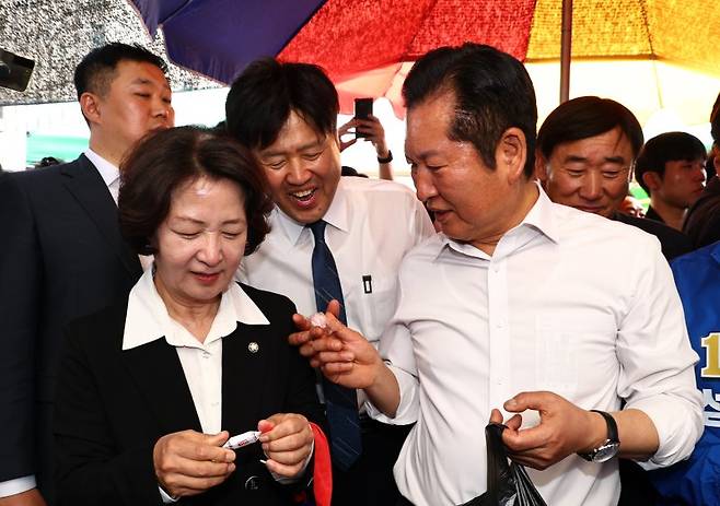 정청래 더불어민주당 대표가 19일 오후 경기 성남시 모란시장 민속5일장에서 김용 전 민주연구원 부원장에게 사탕을 건네고 있다. 뉴시스