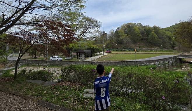 실종 엿새째 밤(13일 밤∼14일 새벽) 늑구가 머문 무수천하마을 안의 삼각섬 모양의 야산을 어린이가 구완천 쪽에 서서 손으로 가리키고 있다. 최예린 기자